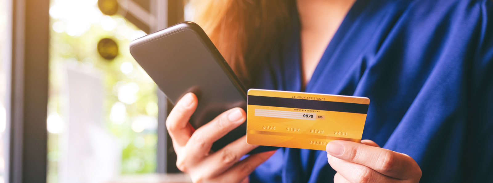 woman holding cellphone in one hand and credit card in the other