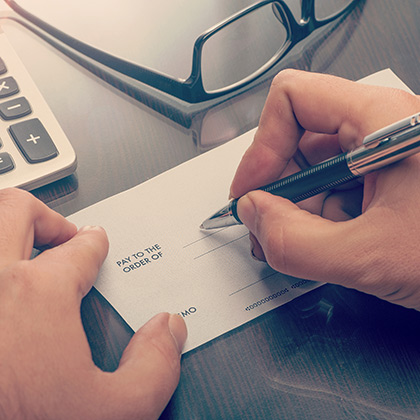 Hands writing a check.