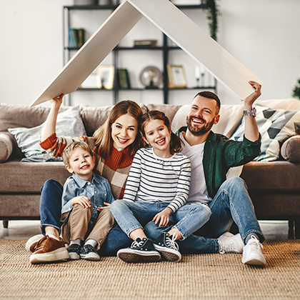 Family under cardboard roof in living room.