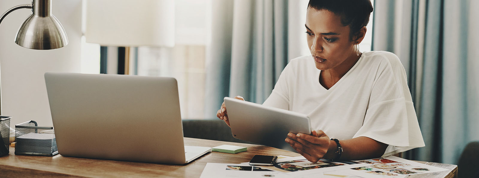 woman sitting at desk focused on working on tablet