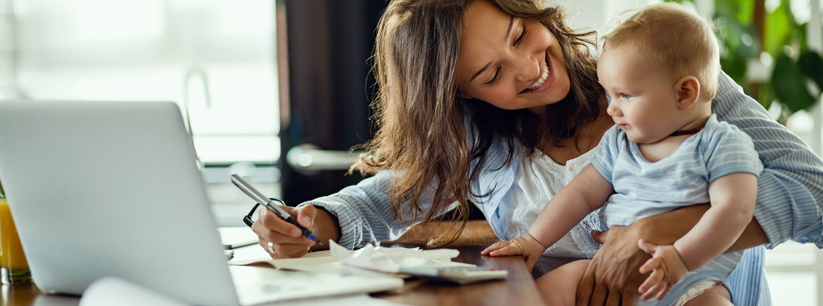 woman holding baby while balancing accounts online