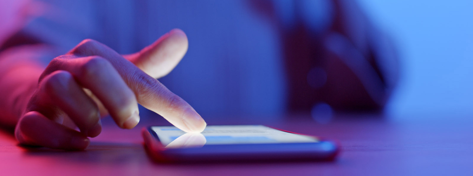 woman's hand scrolling through cellphone lying on table