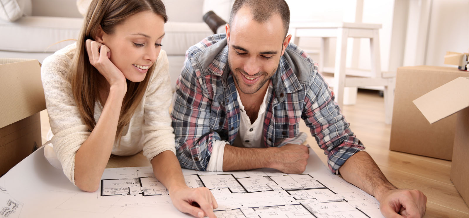 cheerful couple looking at floor plan of house