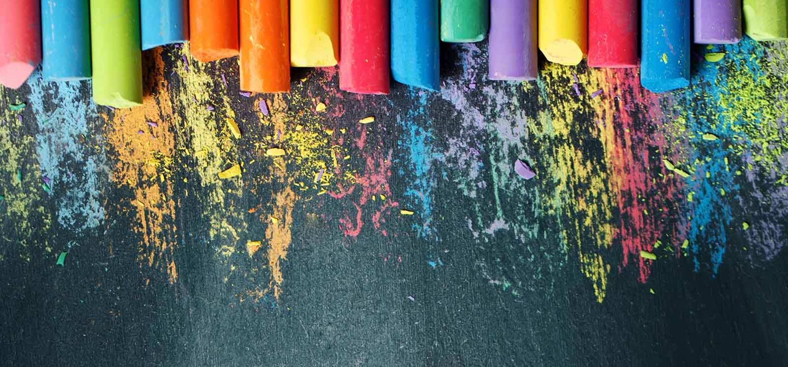 colorful chalk lined up on blackboard