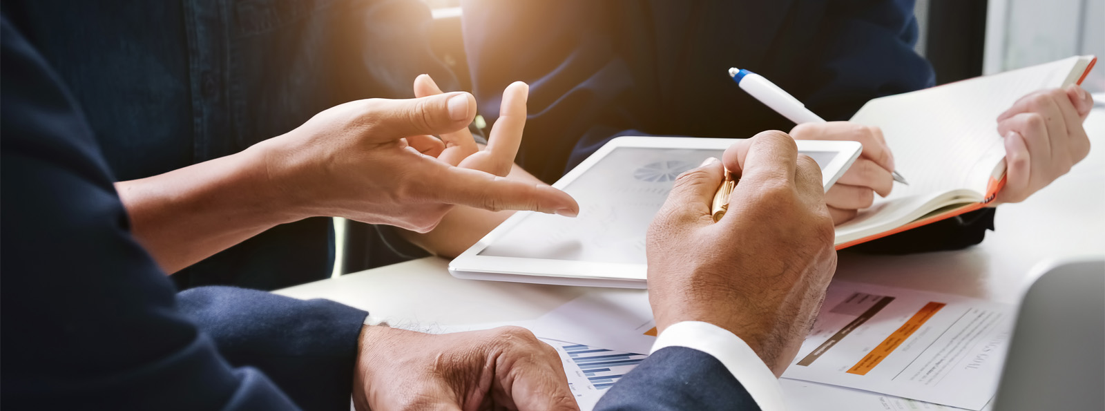 business personnel discussing contents of tablet and taking notes