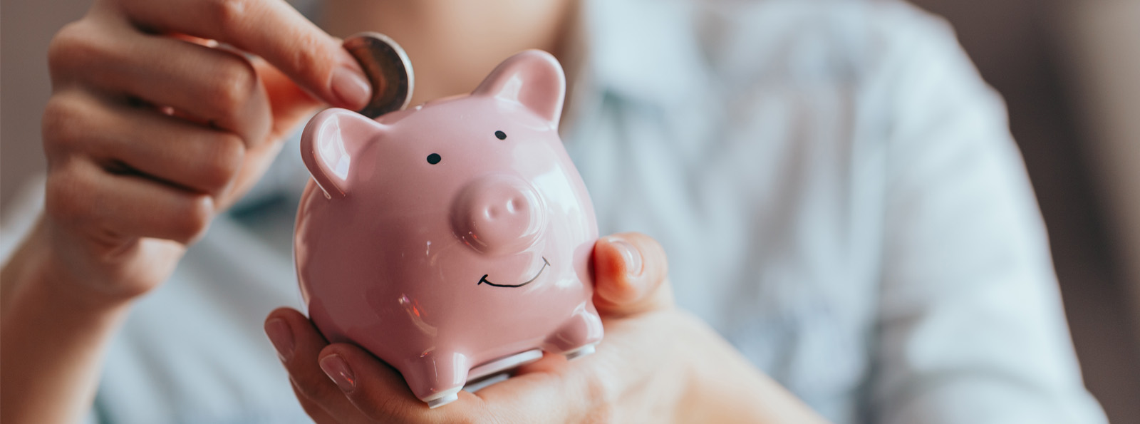 person putting coins in piggy bank