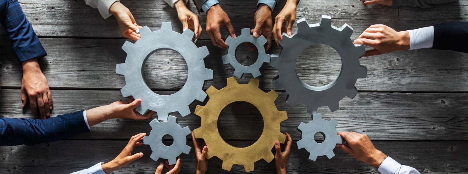 business personnel holding gears near one another so they fit together